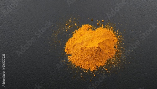 Yellow Ground Spice Pile on Dark Surface in Top View
