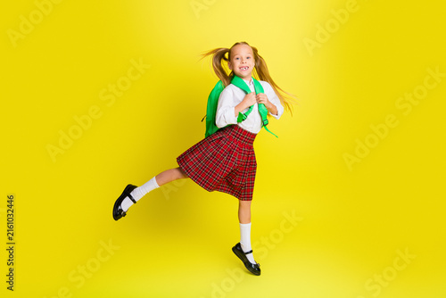Konstfotografi Happy schoolgirl with green backpack jumping against yellow background wearing p