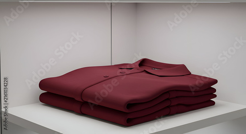 Burgundy polo shirt, folded neatly, rests on a white shelf within a modern wardrobe. Stack of clothing displayed for online retailer.