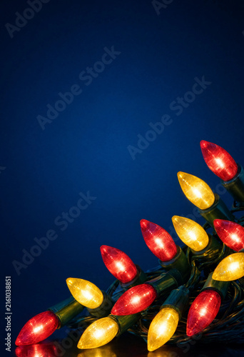 Bright red and yellow christmas string lights against a deep blue background