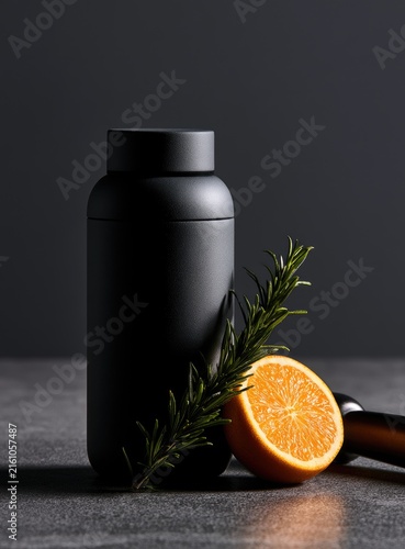 Sleek matte black container beside a citrus slice and herb sprig