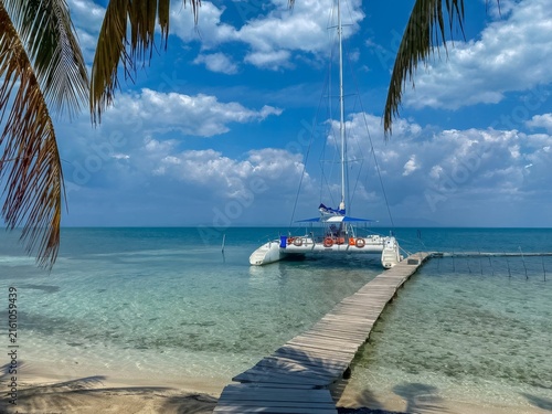 Catamaran waiting at a wooden dock in clear turquoise water on a sunny day