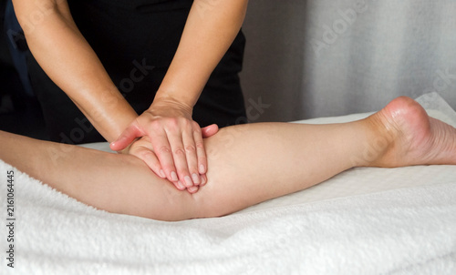 Quadro su tela Massage therapist performing a professional leg and foot massage on a female client