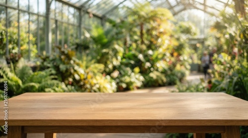 Stylish empty wooden tabletop for product presentation over a blurred modern greenhouse interior backdrop ideal for mockup, branding, and marketing use