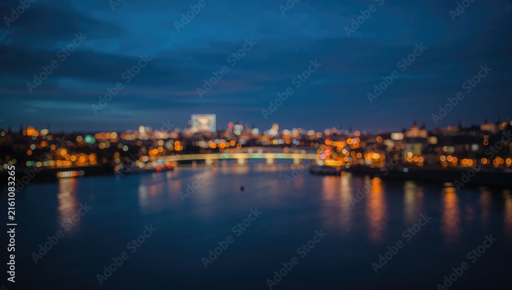 Fototapeta premium Blurred Cityscape Night View Over Water with Soft Lights