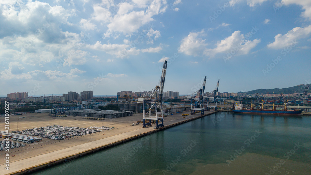 Obraz premium Industrial Port with Cranes and Cargo Vessel Under Blue Sky