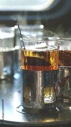 tea in a clear glass cup in a metal cup holder on a table on a train,