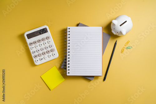 Personal financial planning with calculator, notebook and sticky note on yellow background, flat lay with copy space