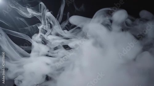 White smoke or vapor swirling on a dark background creating abstract shapes and patterns