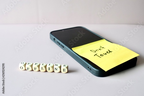 Cuadro en lienzo Angled shot of a smartphone with a Don't Touch reminder note on the screen, accompanied by wooden letter cubes spelling out OFFLINE on the surface