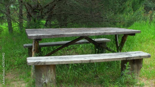 An empty wooden table with a bench for summer picnics in the countryside. An empty resting place during hikes.