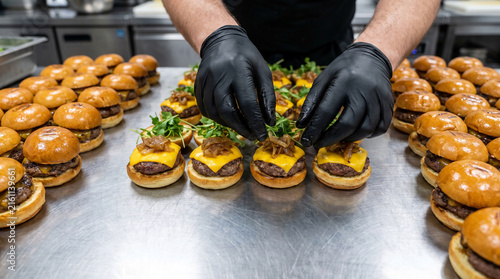 Canvastavla Chef hands assembling gourmet beef sliders and mini burgers on catering tray