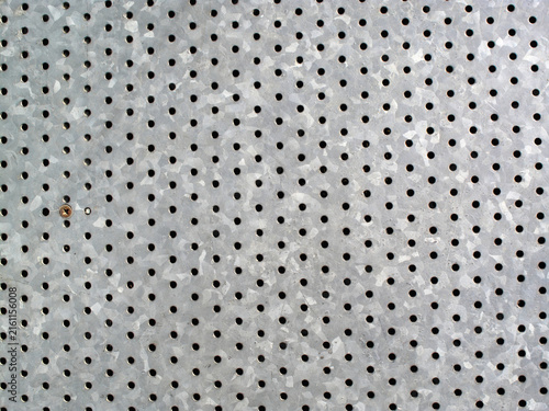 Background texture of a galvanized perforated metal sheet with small circular holes in a regular grid pattern for industrial designs, metallic stock photo image