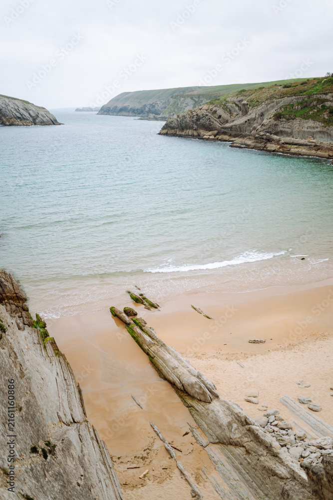 Obraz premium A stunning seascape with large cliffs jutting out of the water. A coastline with large cliffs in the background. Concept of nature and beauty.