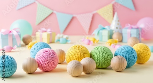 A cheerful celebration setup featuring soft knitted toy balls and natural wooden spheres scattered among pastel party decorations and bunting, sustainable, beige, gentle