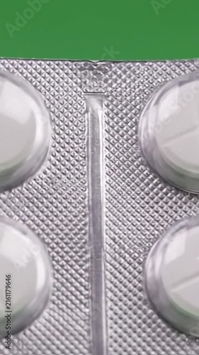 A close-up view of white pills in a blister pack on a green background