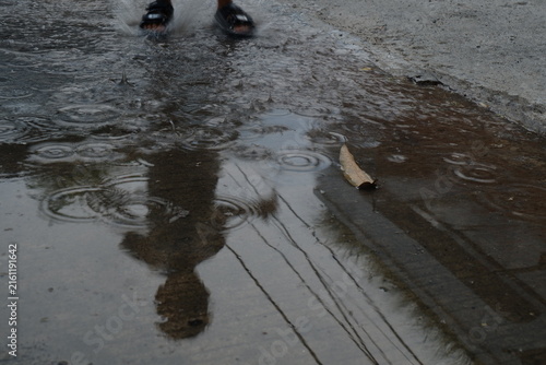 Fotografie Rain ripples on a puddle with reflection