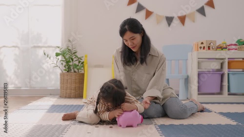 Asian mother and girl playing with pink toy on colorful foam mat in bright home playroom, warm family moment with indoor plant, storage shelf, gentle connection, joyful expression