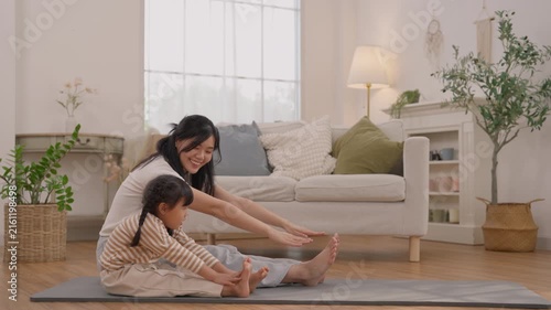 Mother and daughter stretching on yoga mat in bright living room, woman and child sitting together with gentle smiles, family wellness, indoor plants, healthy lifestyle and comfortable home decor