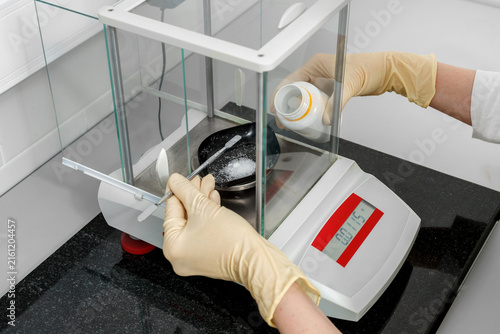 Cuadro en lienzo Specialist in gloves weighing a reagent on an analytical balance in a laboratory