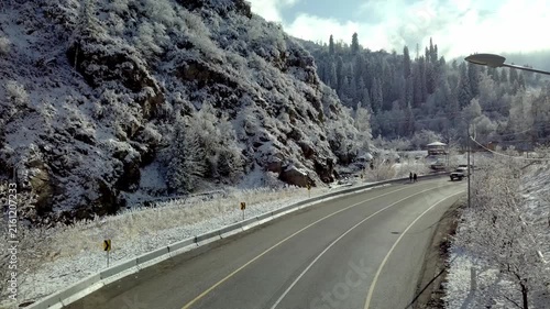 Empty asphalt mountain road with snow covered slopes and pine trees in winter landscape