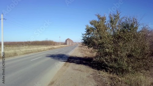 Empty asphalt country road stretching into the distance under clear blue sky on sunny autumn day