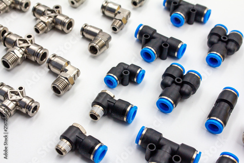 Assortment of pneumatic push in quick release fittings made of metal and plastic on white background