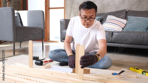 senior Man furniture assembly wood home tool scene focused adult building wooden frame on living room floor near sofa
