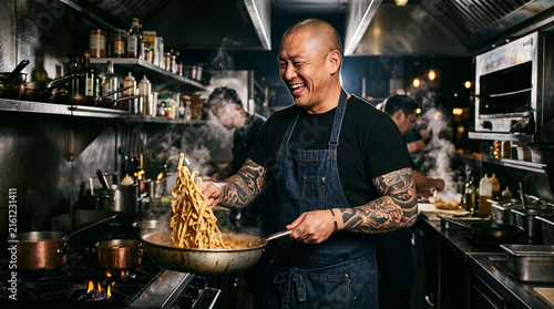 Obraz na płótnie Chef smiling proudly while cooking delicious noodles inside a busy kitchen.