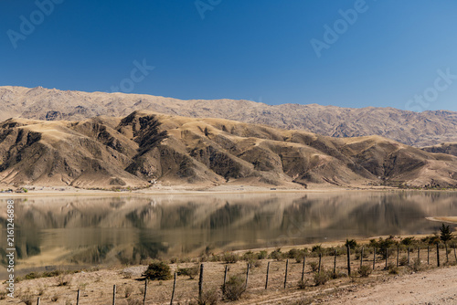 La angostura dam lake reflecting the dry mountains along provincial route 307, a scenic drive through the arid winter landscape of tucumán, argentina