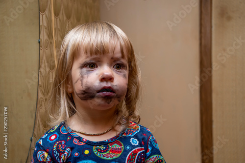 Foto Worried little girl with smeared black makeup standing indoors near wall