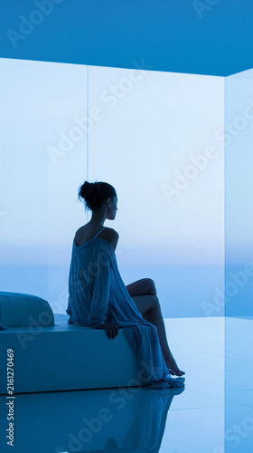 Silhouette of a young woman in a serene blue-toned modern interior.