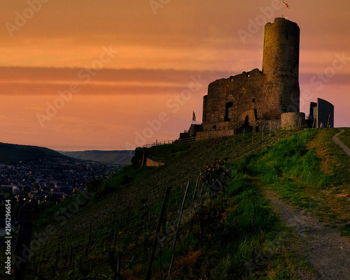 Photography Castle stands on a hill at sunset overlooking a valley and a village in the dist