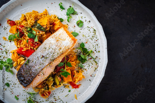 Fried salmon fish fillet with pumpkin and sweet potato rosti gratin served as top view on a design plate