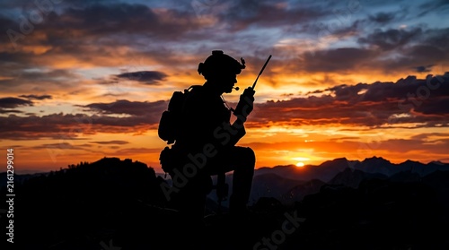 Silhouette of a hiker with a backpack and walking stick watching a vibrant sunset over mountainous terrain at dusk