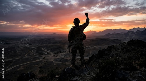 Silhouette of a soldier celebrating victory on rugged terrain during a vibrant sunset scenery