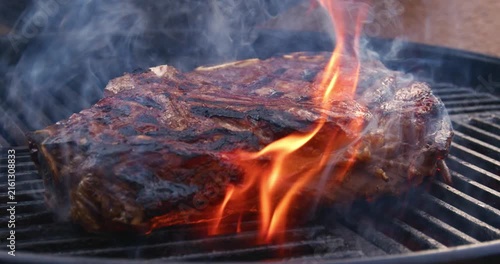 Barbecue dry aged entrecote roast beef steaks grilled as close-up on a charcoal grill with fire and smoke