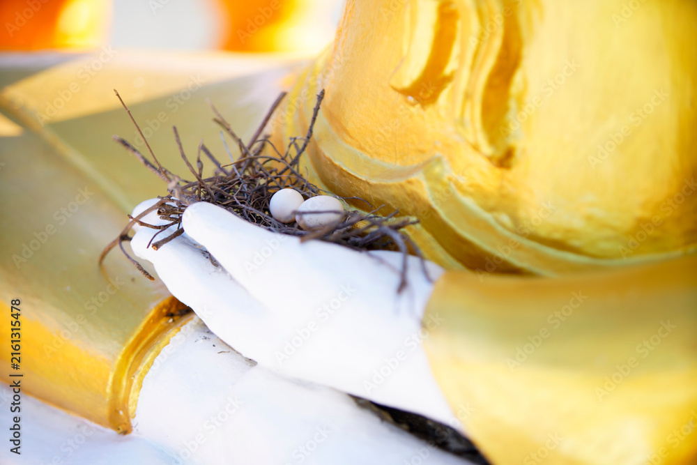 Fototapeta premium Close-up of a nest with eggs on religious statue's base showing faith and spirituality