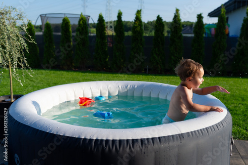 Boy playing with water in inflatable garden hot tub