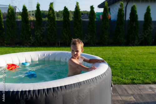Toddler boy playing in inflatable hot tub during summer