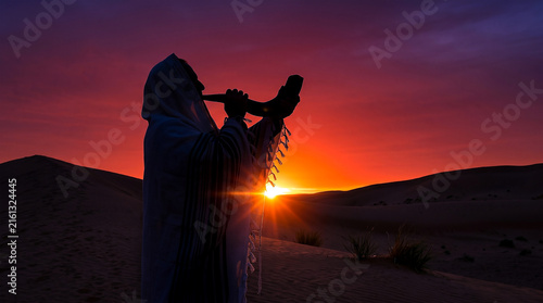 A devoted man blowing the shofar during Selichot prayers at sunrise in the desert for the Rosh Hashanah holiday, reflecting spiritual tradition and faith