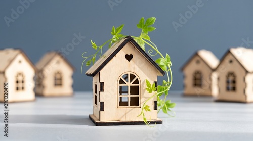 Eco-friendly wooden house model with green plant. Sustainable real estate concept. Miniature timber homes for mortgage and housing market.