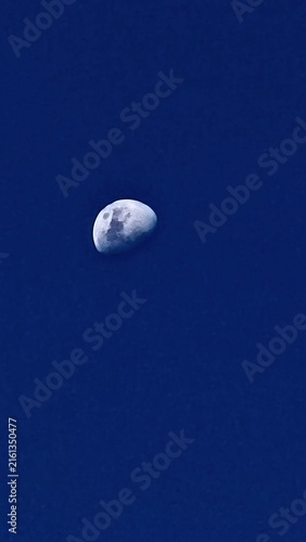 Cuadro en lienzo Serene night sky featuring a glowing half moon in deep blue cosmic background