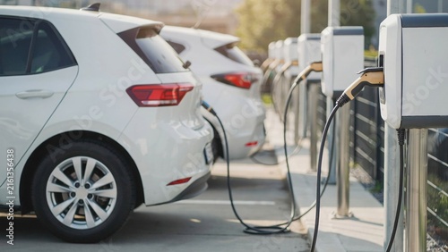 Row of modern electric vehicles parked at charging stations in a clean outdoor urban parking lot setting