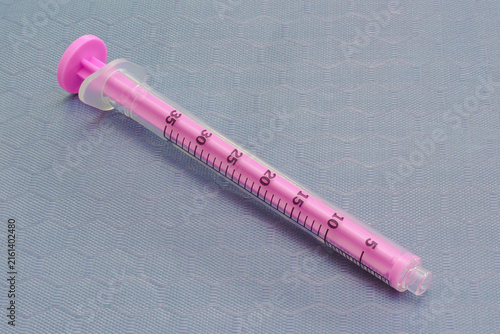 Empty medical syringe on a clinical gray surface.