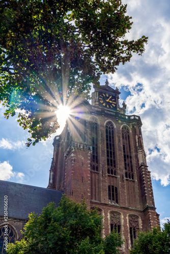The sun is just slipping past the tower of the Grote Kerk, a prominent historic church with a tower approximately 65 meters high in Dordrecht