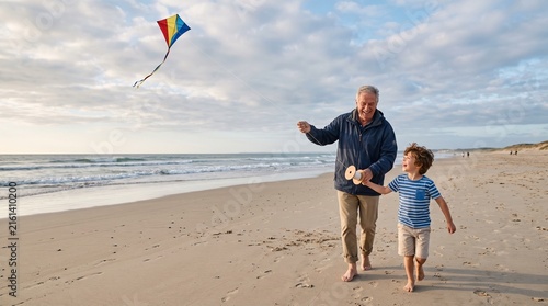 Grandfather and grandson enjoy flying a kite together on a sandy beach