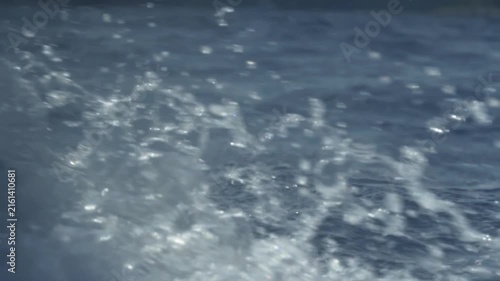 Sailing boat wake splashing on deep blue ocean water