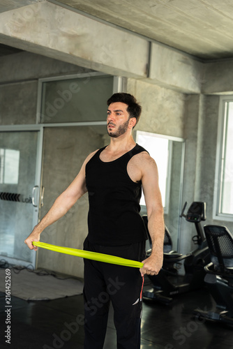 Fotografie Adult Caucasian man holding green resistance band across hips in modern gym, pre