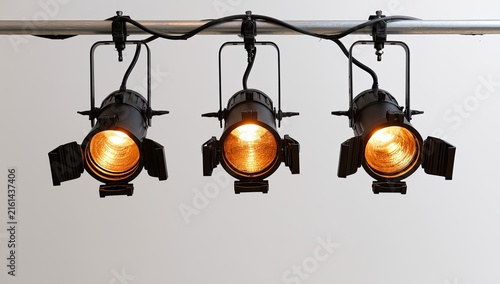 Three Stage Lights Illuminated on a Track Against a White Background.